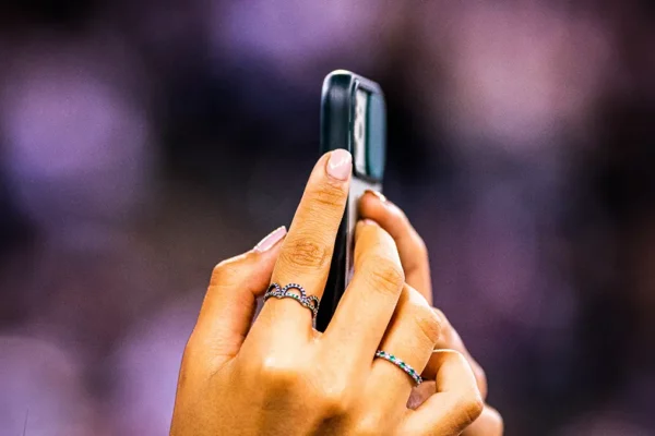 Mano che riprende con lo smartphone durante un evento, pubblico e luci di scena sfocati sullo sfondo